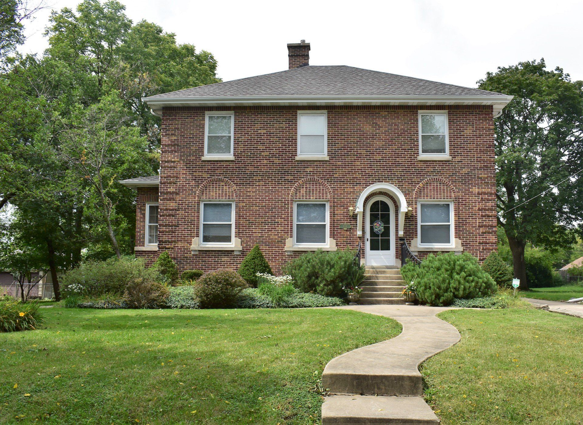 A large brick house with a walkway leading to the front door