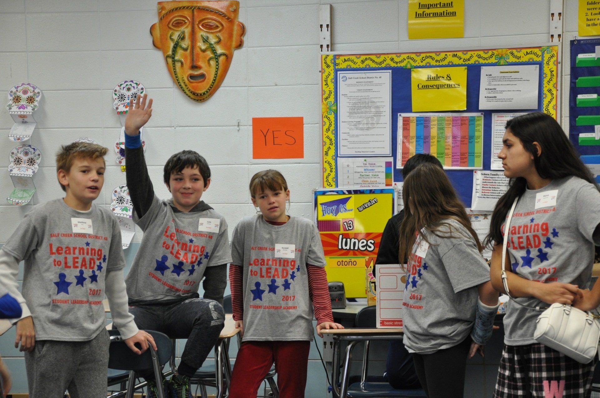 A group of children wearing shirts that say learning leaders are standing in a classroom.