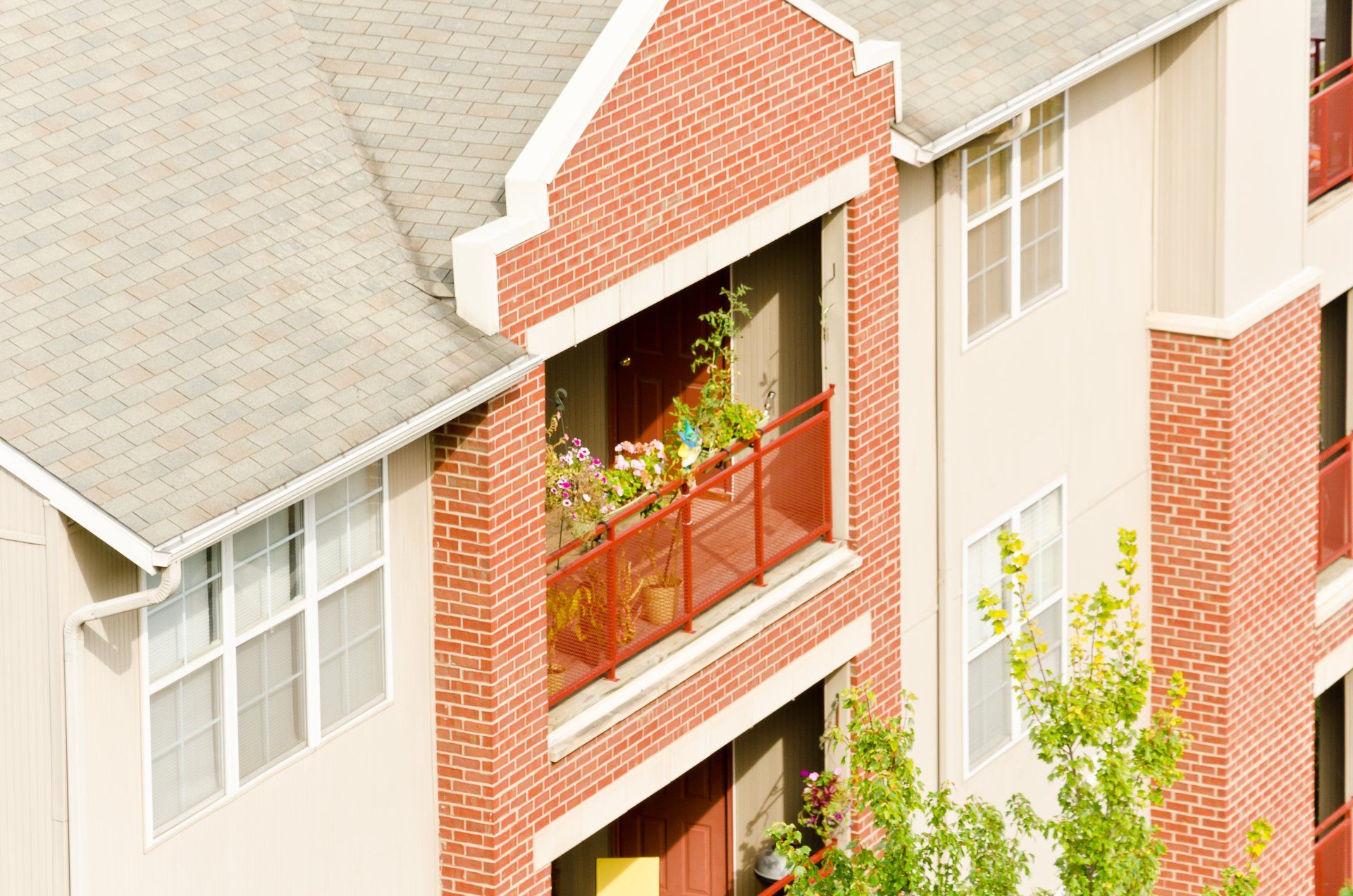 A brick apartment building with a balcony with flowers on it