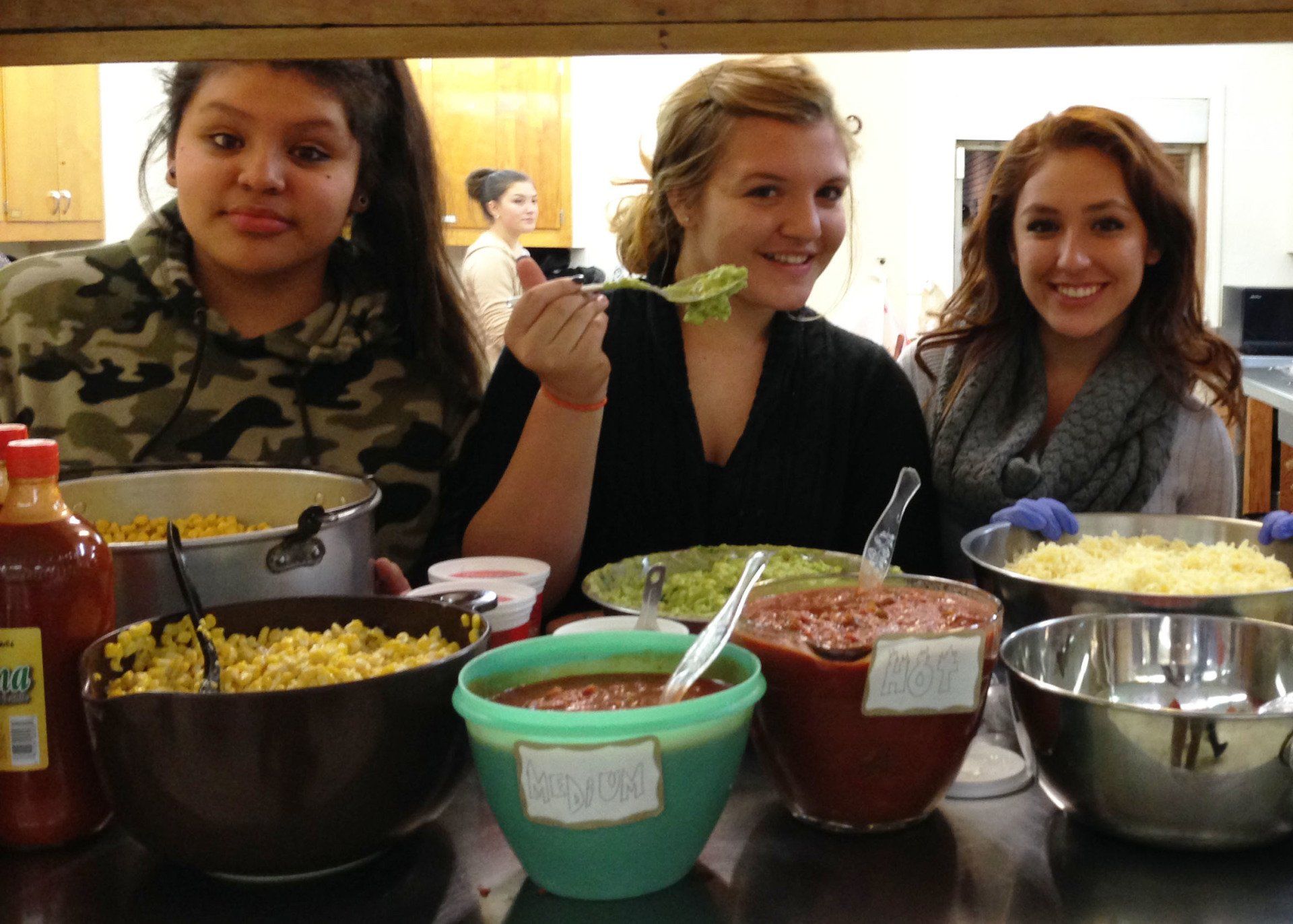 Three women are sitting at a table with bowls of food