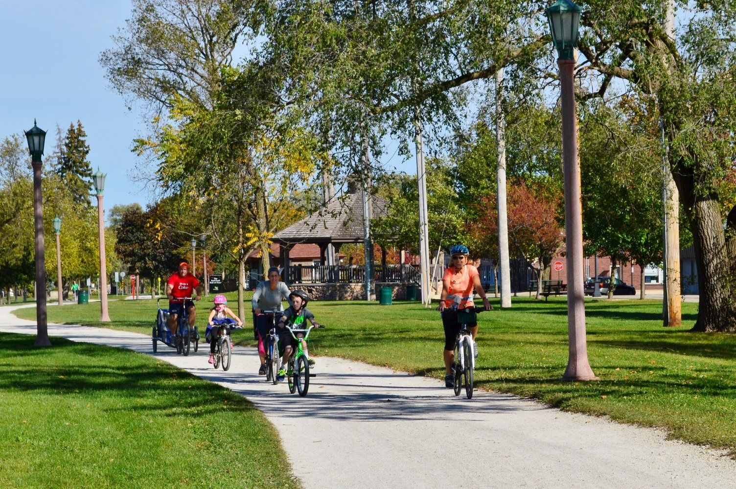 A group of people are riding bikes down a path in a park.