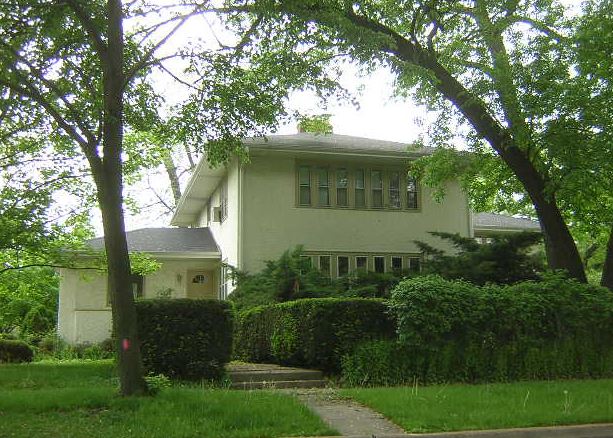 A white house is surrounded by trees and bushes