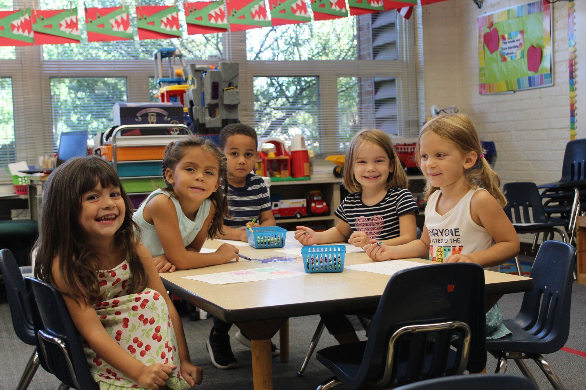 A group of young girls are sitting at a table in a classroom.