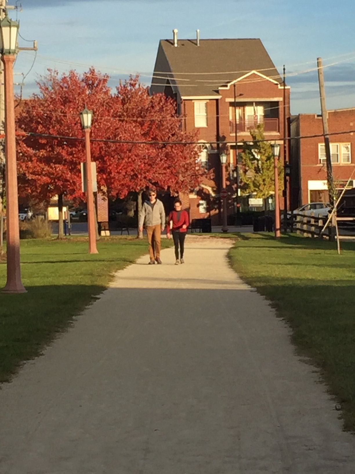 Two people are walking down a path in a park