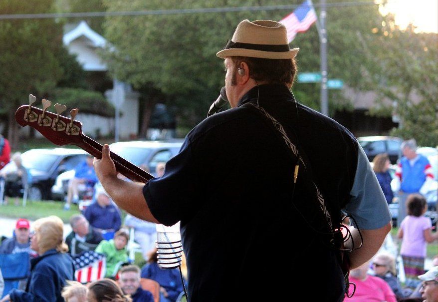 A man in a hat is playing a guitar in front of a crowd