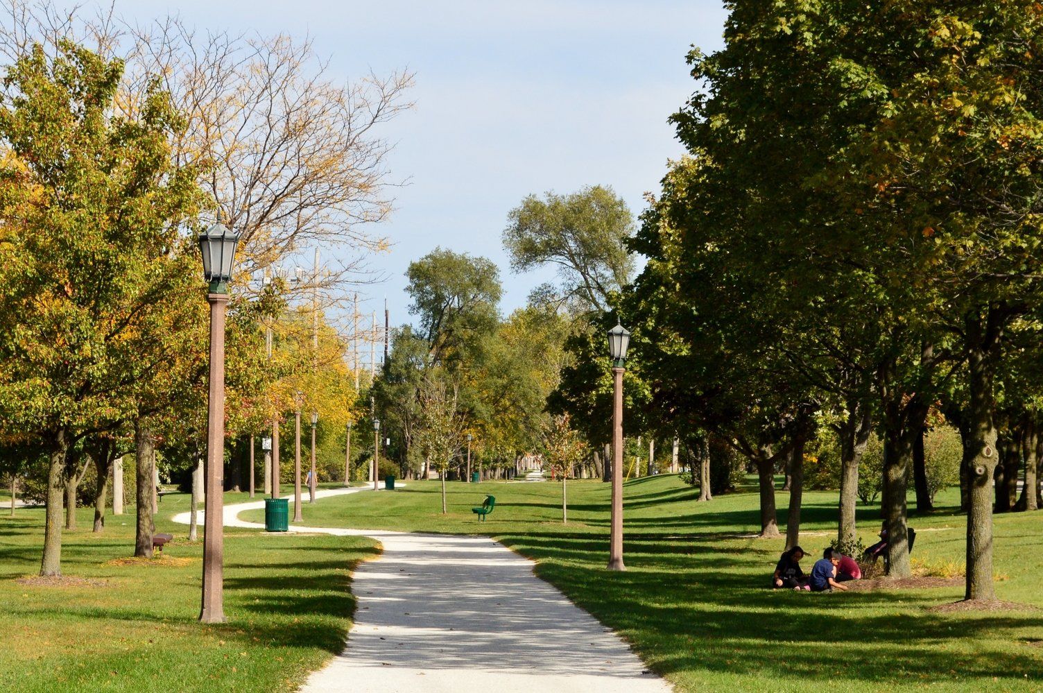 A group of people are sitting on the grass in a park.