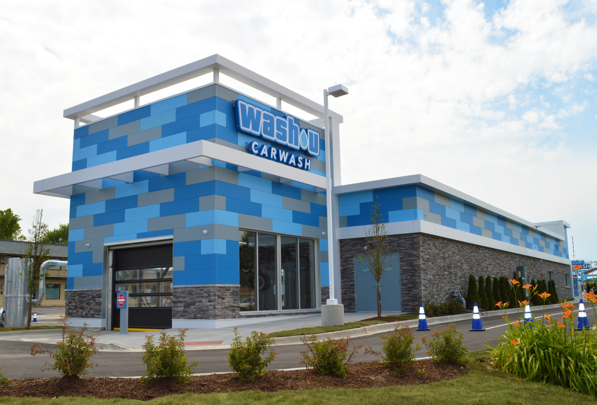 A blue and white building with a car wash inside of it.