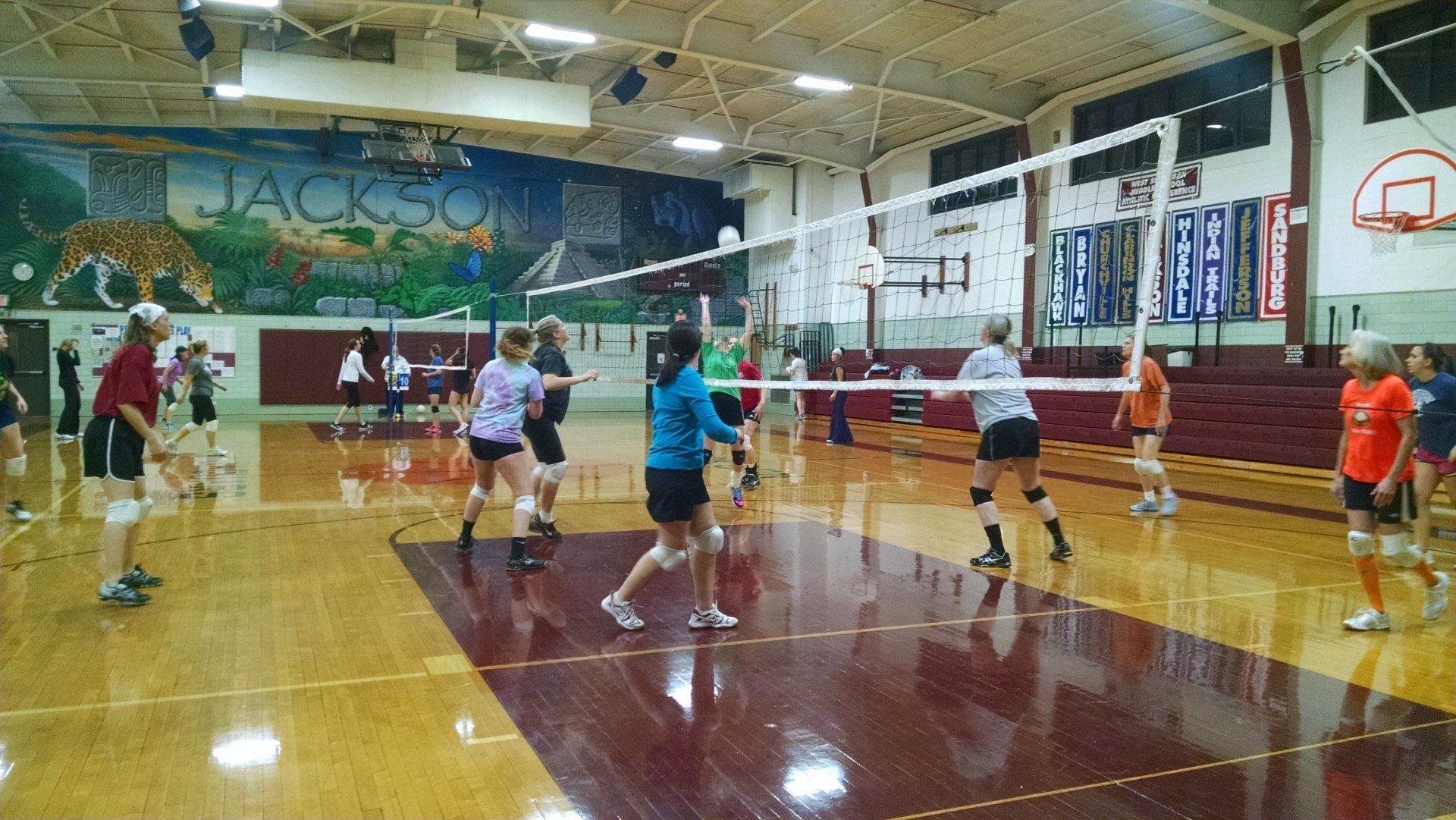 A group of people are playing volleyball in a gym.
