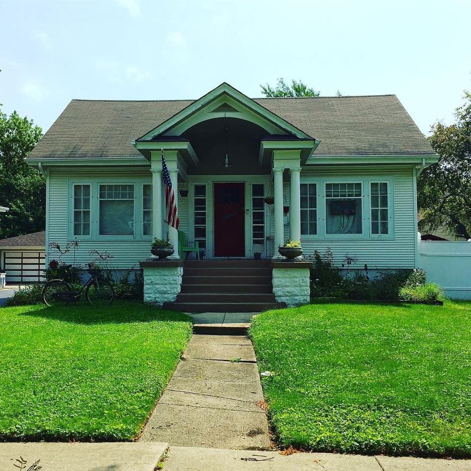 A white house with a red door and an american flag