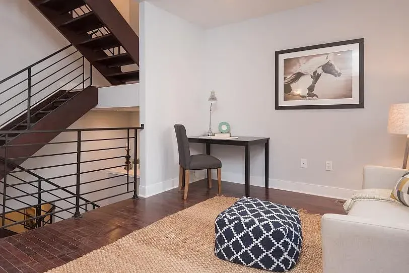 A living room with a staircase and a desk
