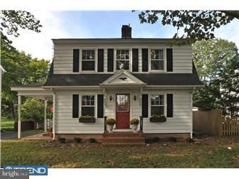 A white house with black shutters and a red door