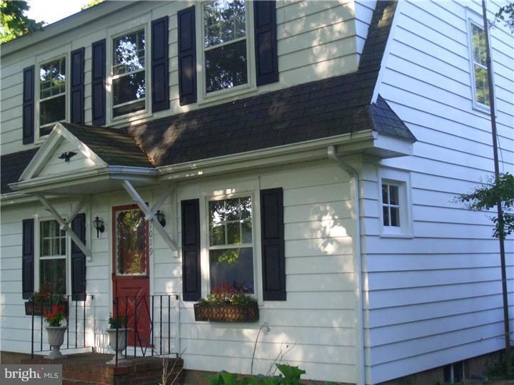 A white house with black shutters and a red door