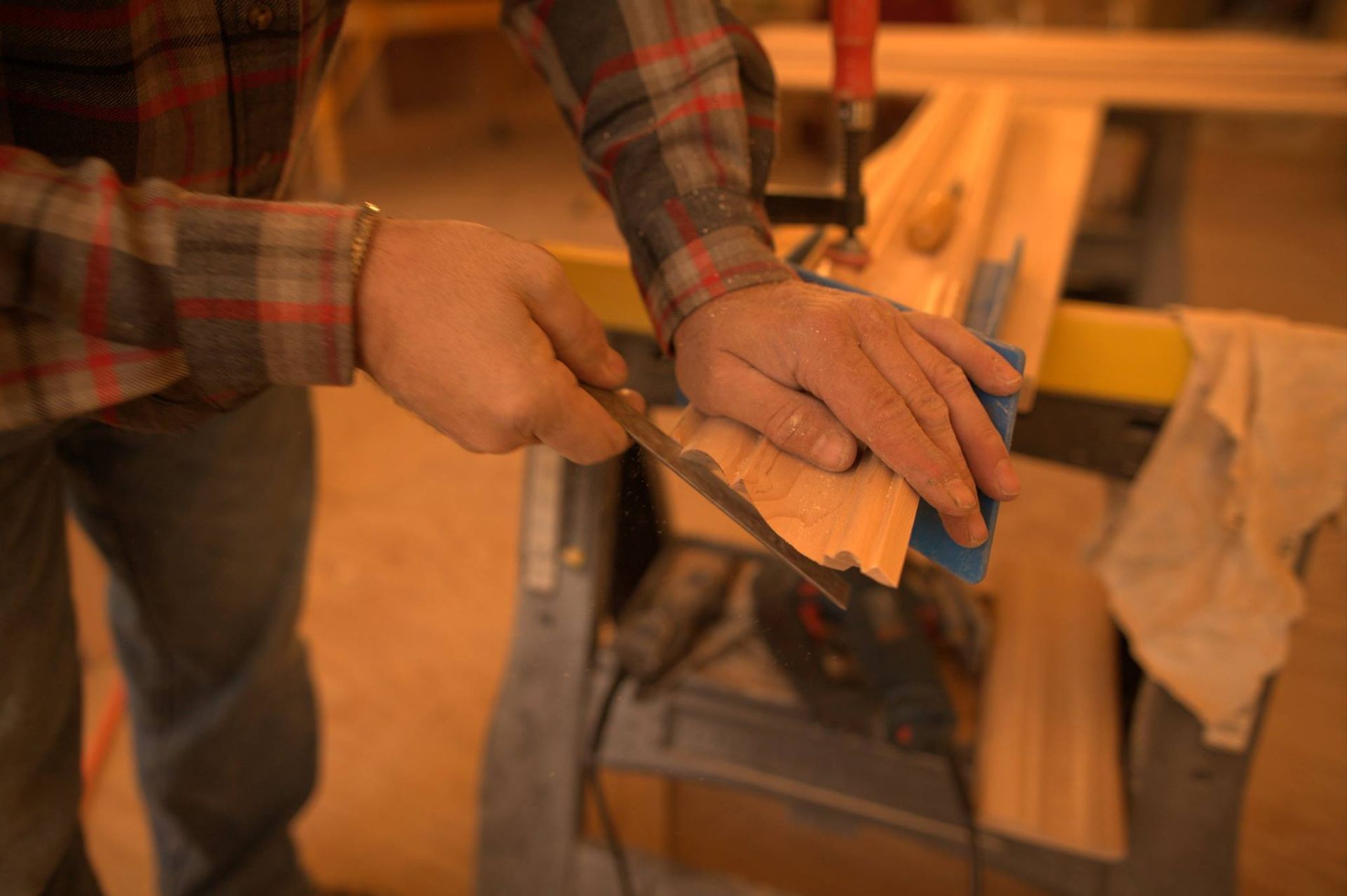 A man is sanding a piece of wood with a sander.