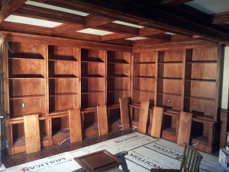 A room with a lot of wooden shelves and a chair