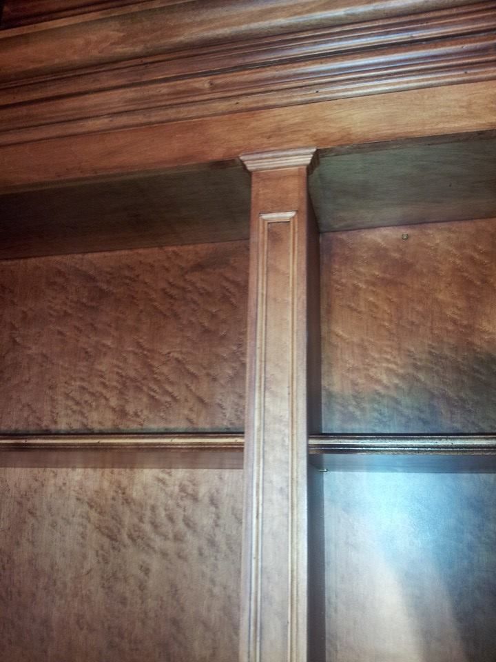 A close up of a wooden shelf with a wooden column in a room.
