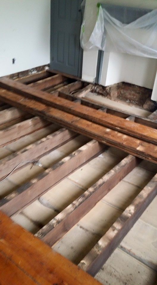 A wooden floor in a room with a fireplace in the background.