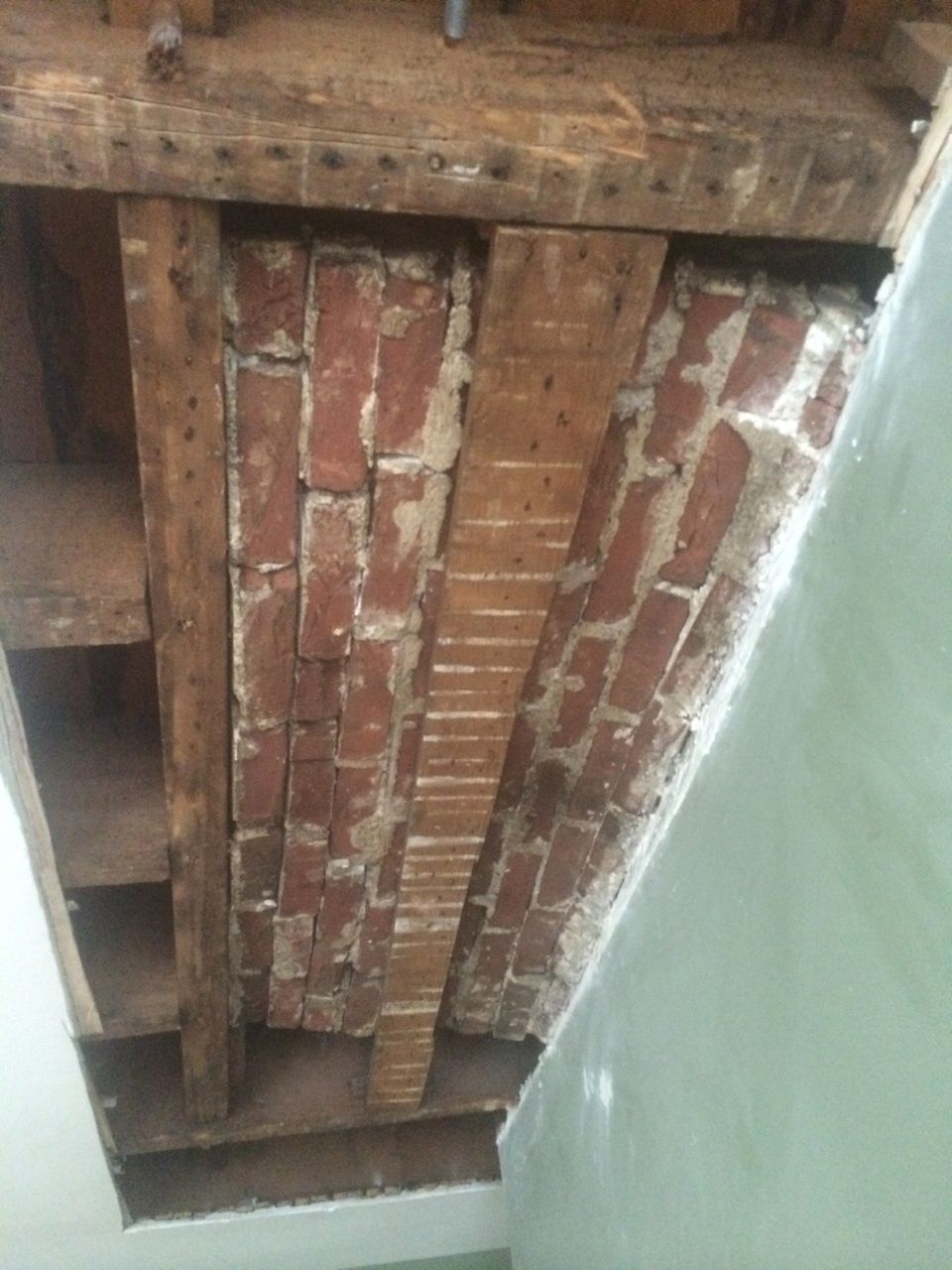 A ceiling with bricks and wooden beams in a room