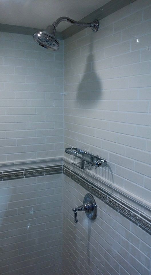 A shower with a shower head and a soap dish on the wall.