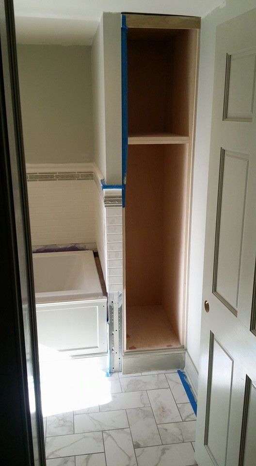 A bathroom with a bathtub and a shelf in the corner.