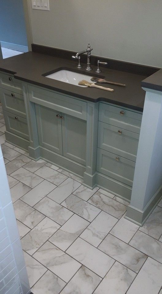 A bathroom vanity with a sink and a marble floor.
