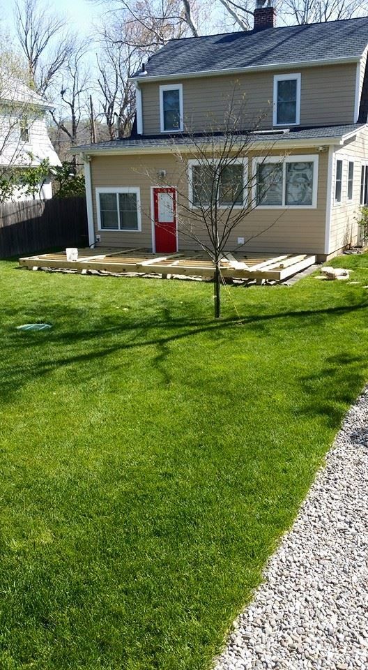 A house with a red door and a large lawn in front of it.