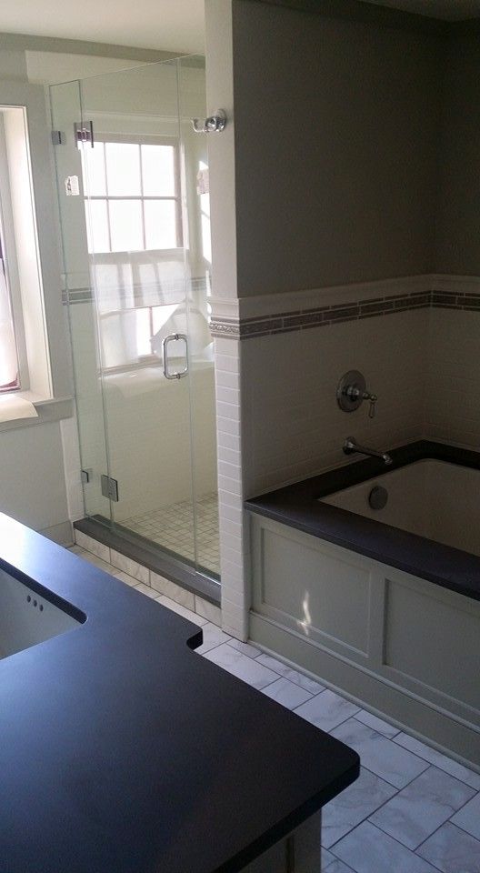 A bathroom with a tub and a shower with a glass door.