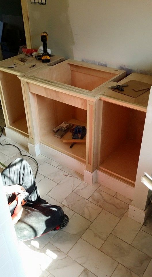 A person is standing next to a sink in a kitchen under construction.