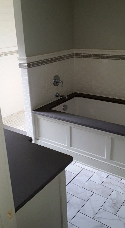 A bathroom with a bathtub and a black counter top.