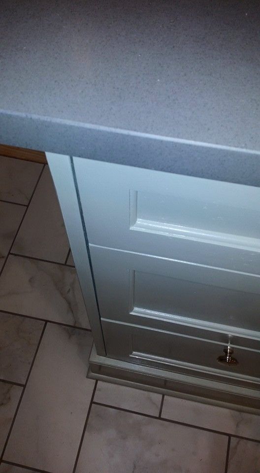 A kitchen counter with white cabinets and a gray counter top