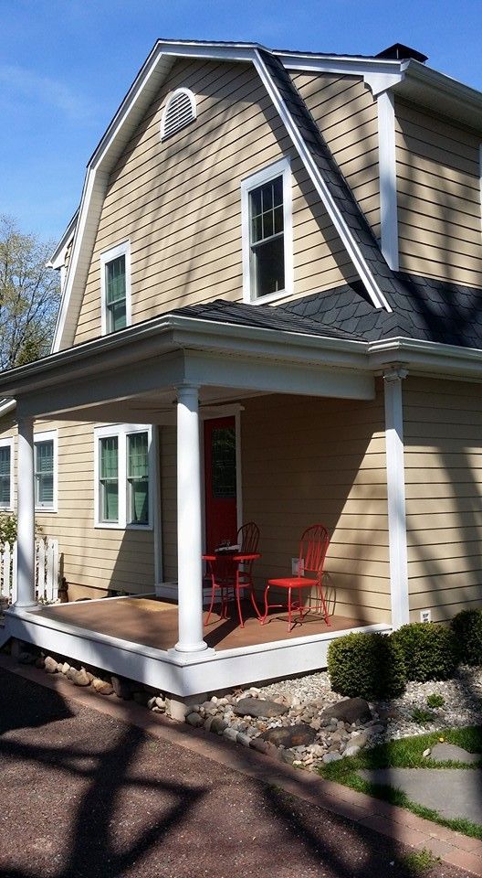 A house with a porch and red chairs on it