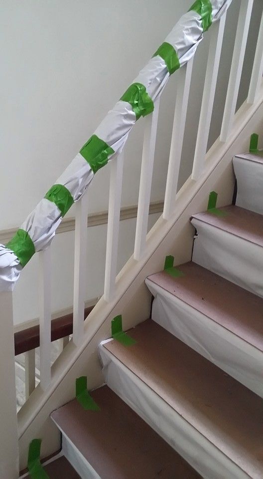A staircase with a white railing and green tape on it.