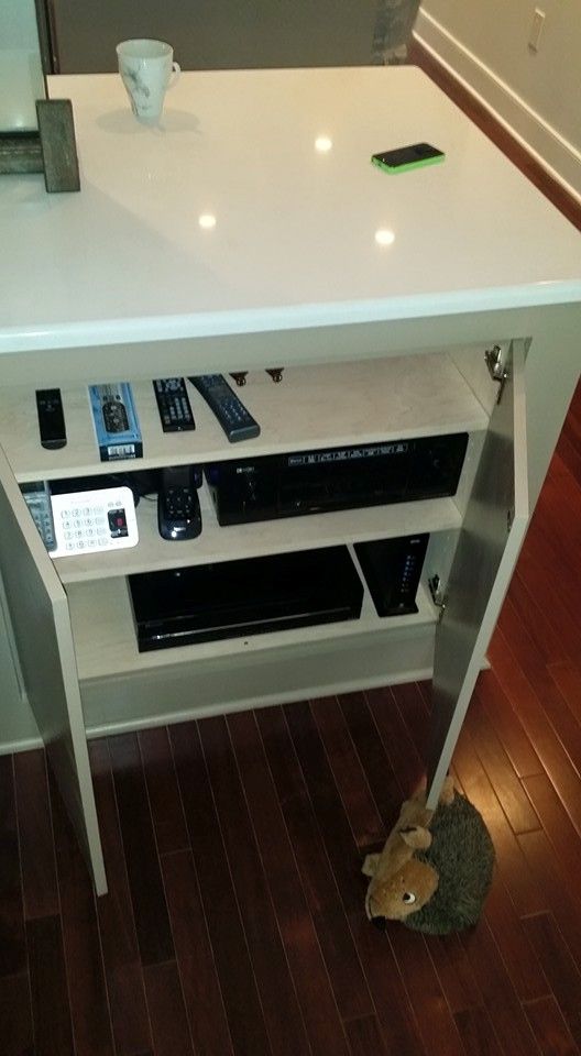 A white table with a bunch of remote controls on it.