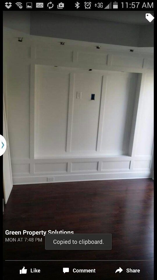 A cell phone screen shows a room with a wooden floor and white cabinets.
