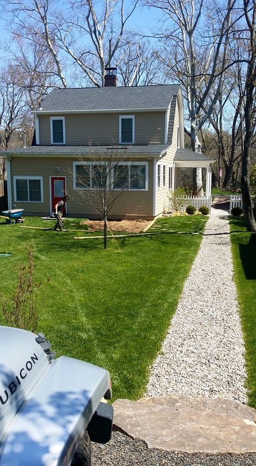 A jeep is parked in front of a house with a gravel path leading to it.