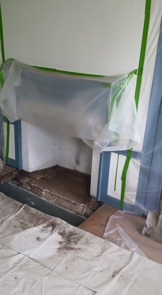 A fireplace is covered in plastic while being painted.