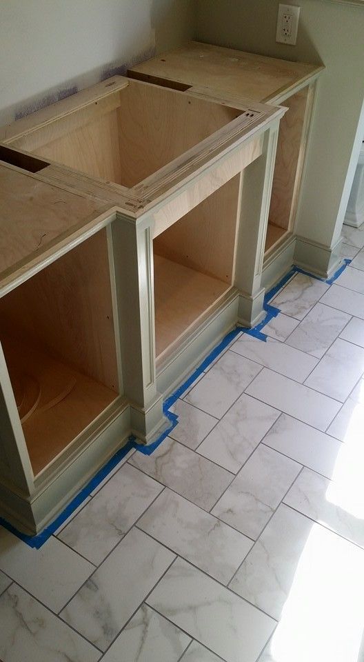 A kitchen with a sink , cabinets , and tile floor.