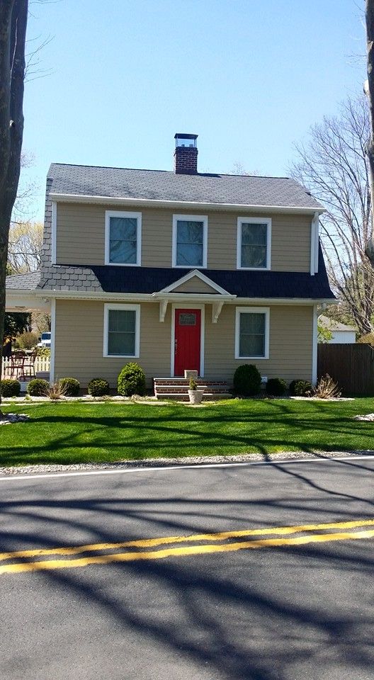 A house with a red door is sitting on the side of the road.
