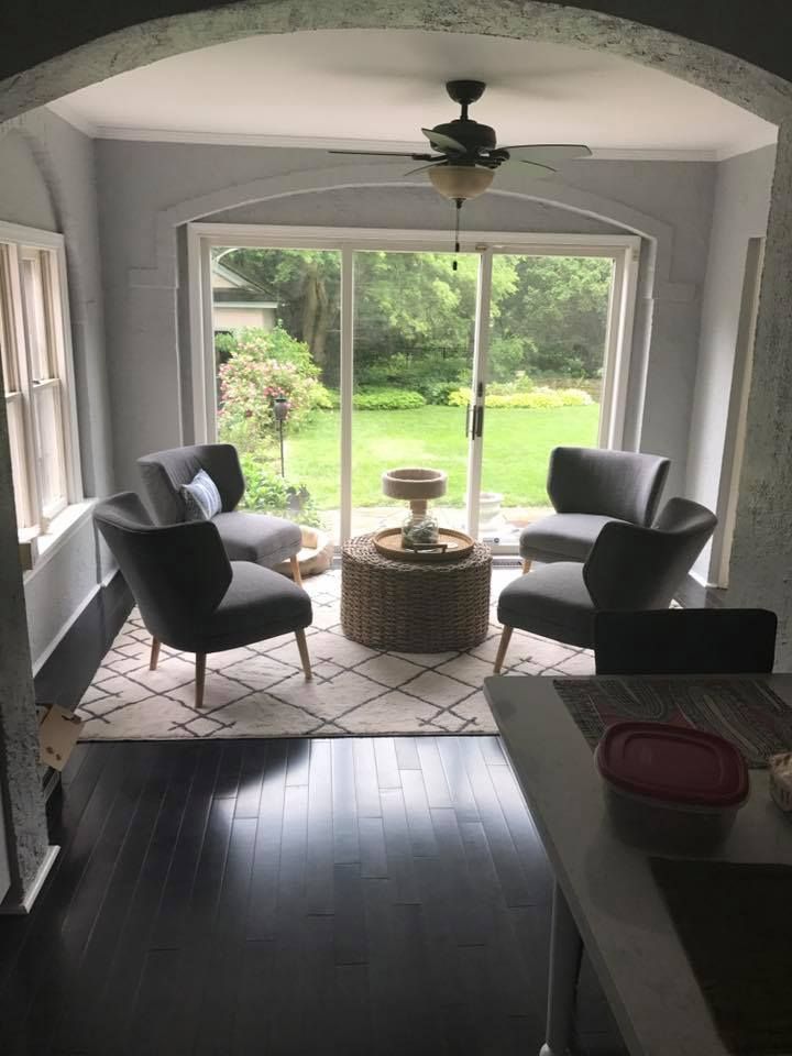 A living room with two chairs , a coffee table and a ceiling fan.