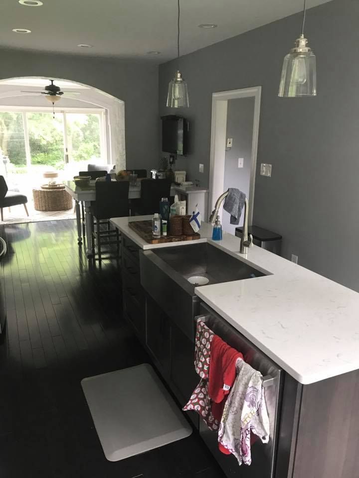 A kitchen with a stainless steel sink and a white counter top.