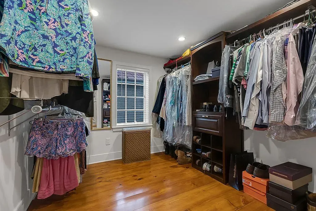 A walk in closet filled with lots of clothes and shoes.