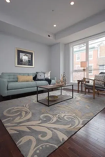 A living room with a couch , chairs , coffee table and rug.
