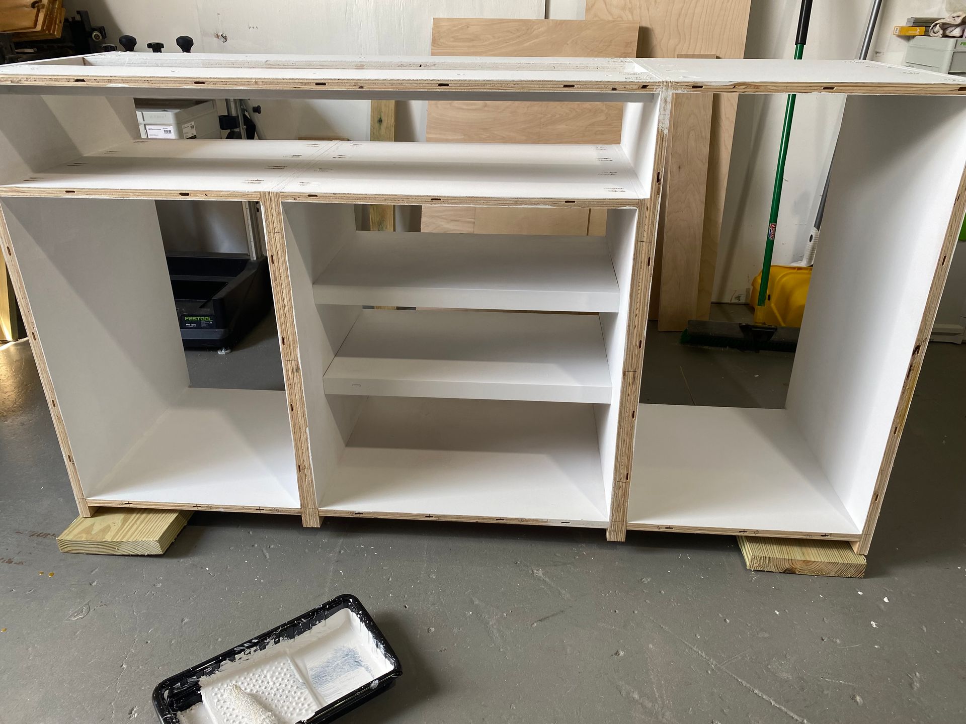 A white cabinet is being painted in a garage