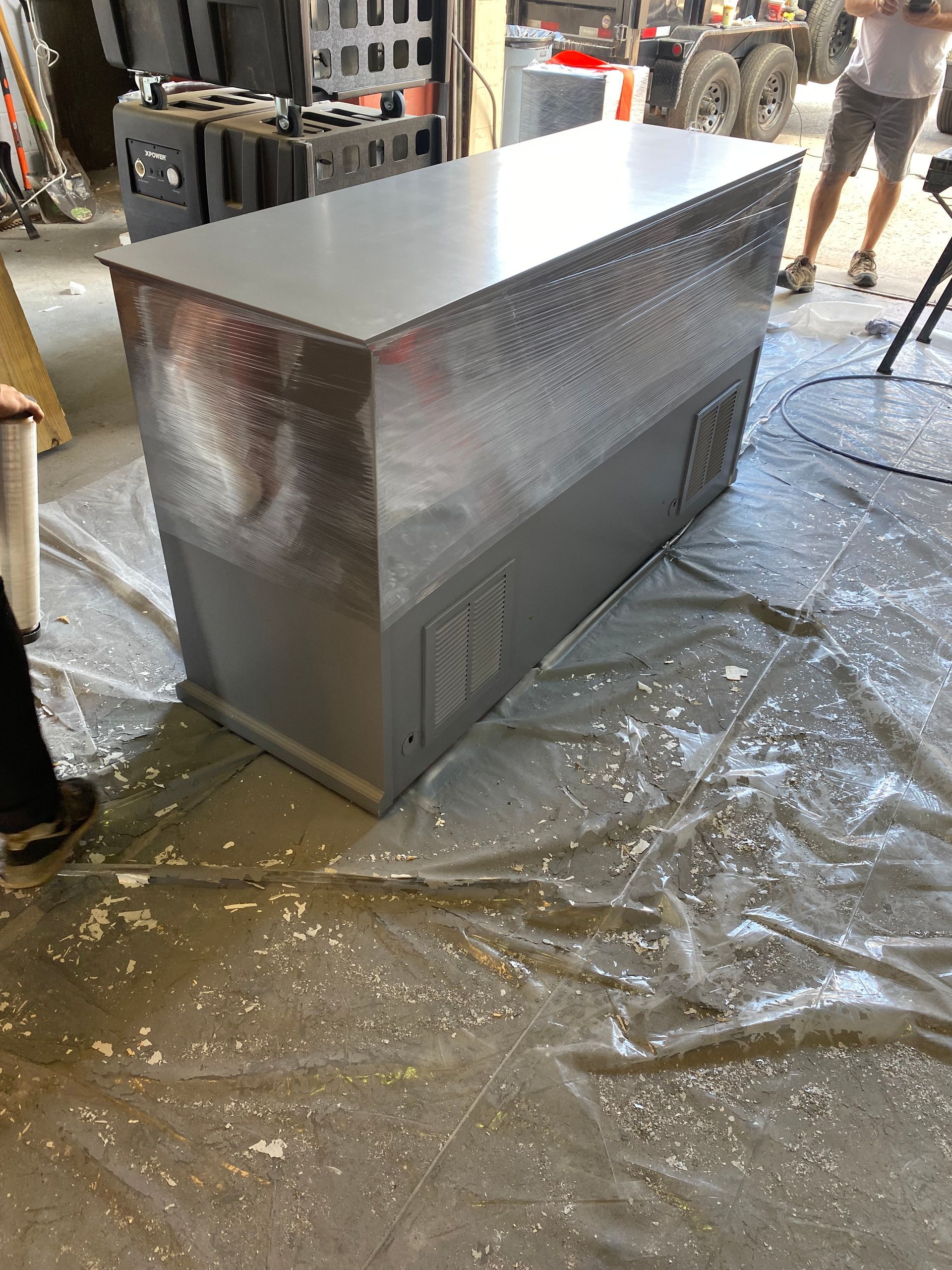 A large metal box is sitting on the floor in a garage.