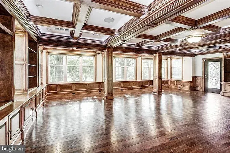 A large empty room with hardwood floors and a wooden ceiling.