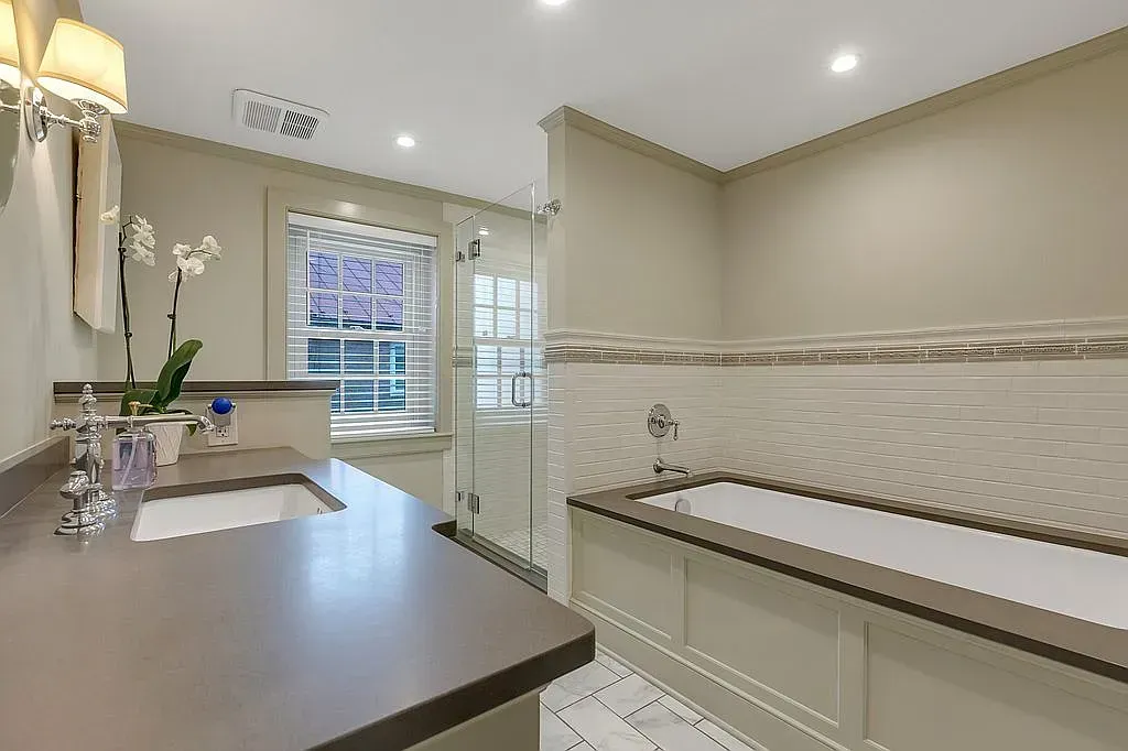 A bathroom with a tub , sink , and window.