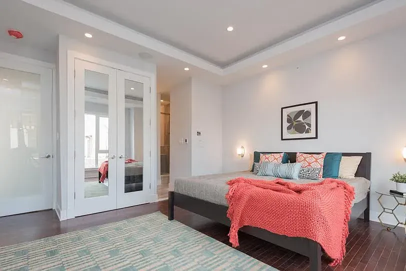 A bedroom with a large bed and a rug.