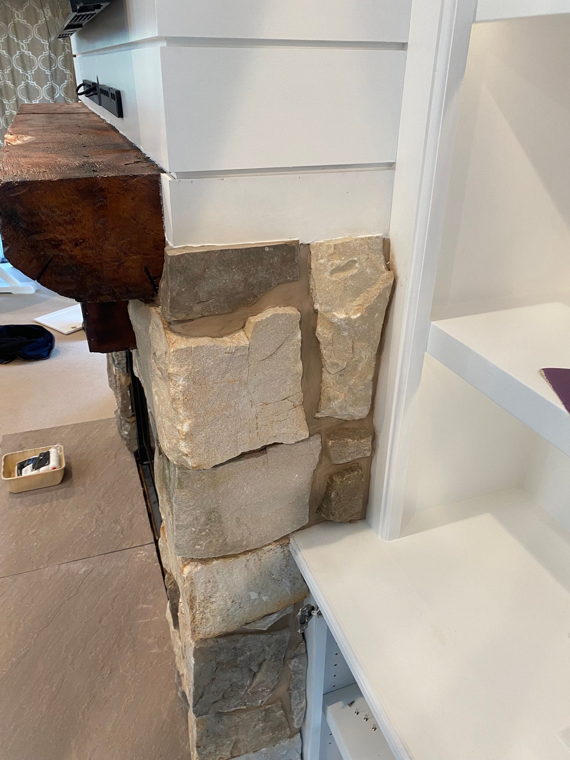A stone fireplace with a wooden mantle in a living room.