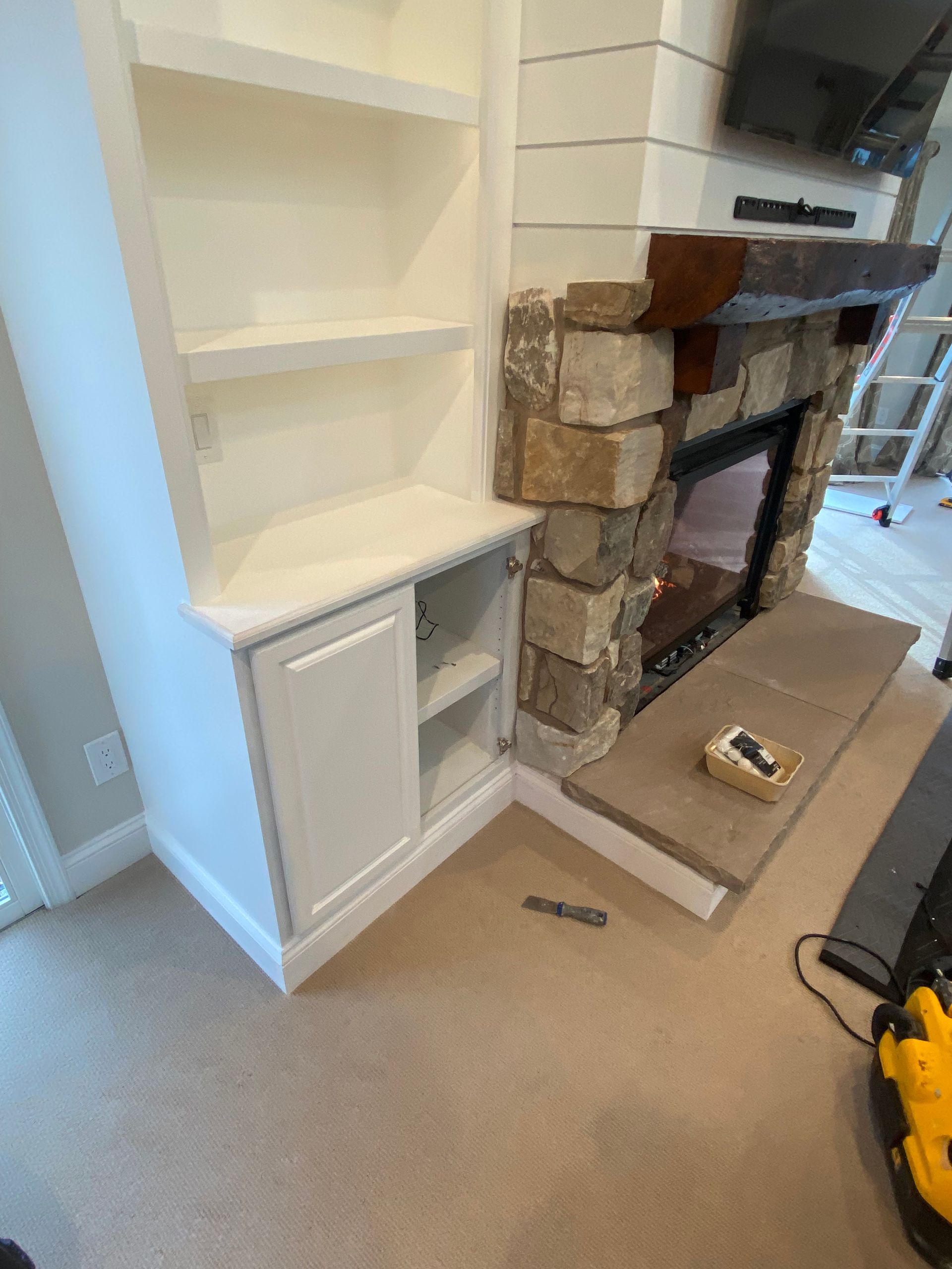 A living room with a fireplace , shelves , and a television.