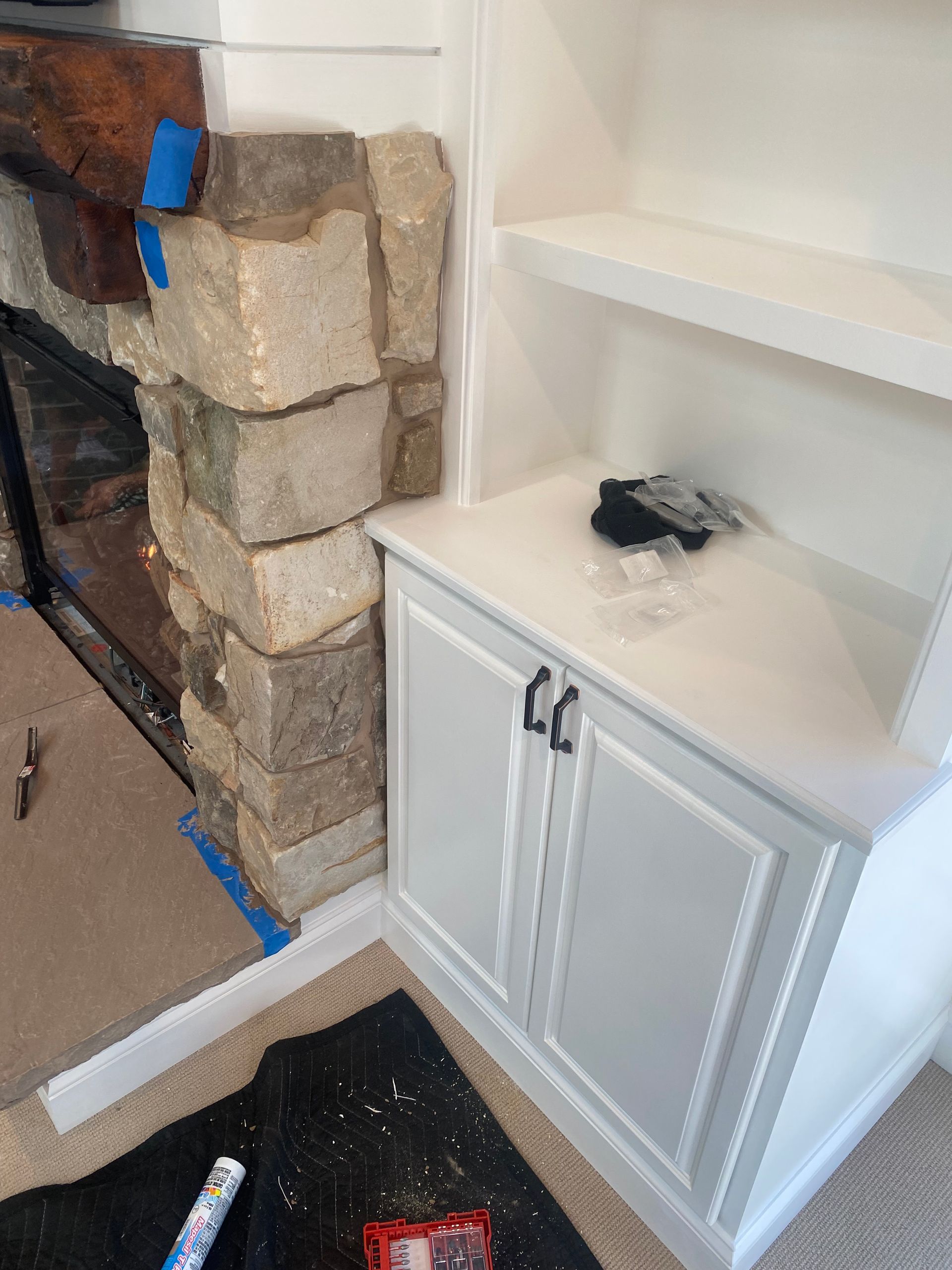 A white cabinet is sitting next to a stone fireplace