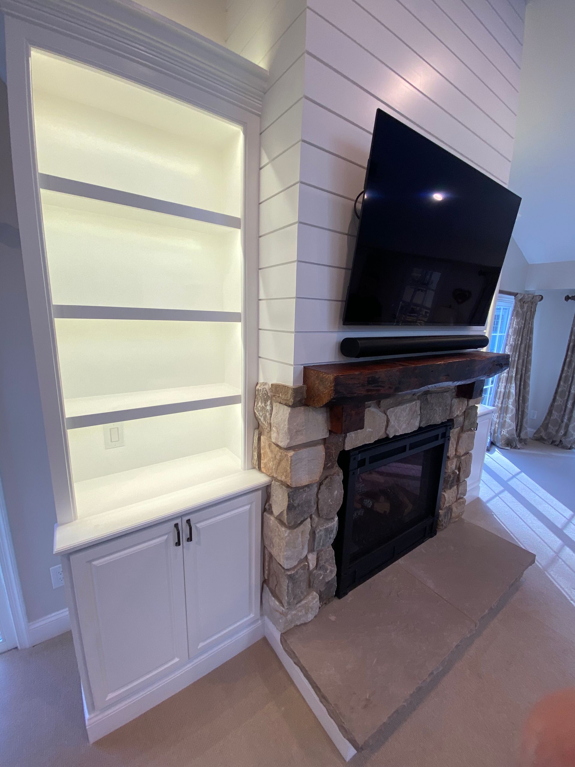 A living room with a fireplace and a flat screen tv on the wall.